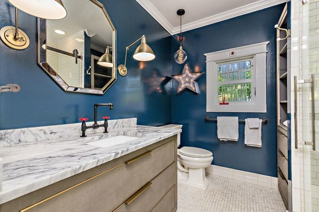 Finished navy bathroom with brass sconces and marble vanity